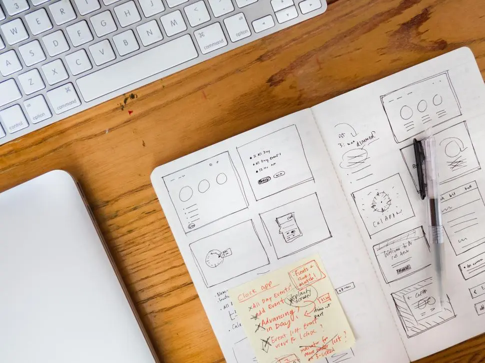 A notebook with hand-drawn website wireframes beside a keyboard